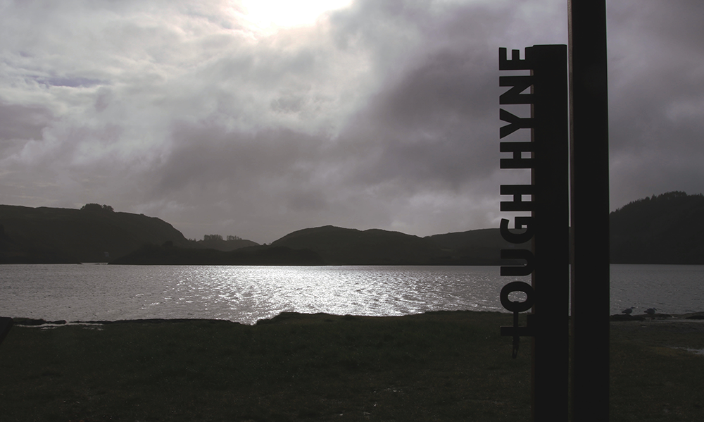 Tranquil lake near Skibbereen, reflecting the surrounding lush greenery and clear skies, symbolizing the serene foundation of time banking in Ireland.