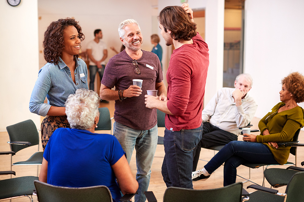 A group of diverse individuals engaging in lively conversation after a meeting at an Irish community center.