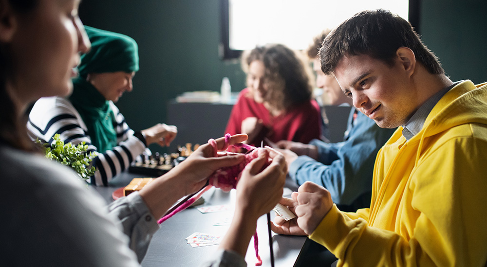 A diverse group, including a disabled individual, engrossed in card and board games at an Irish community center.