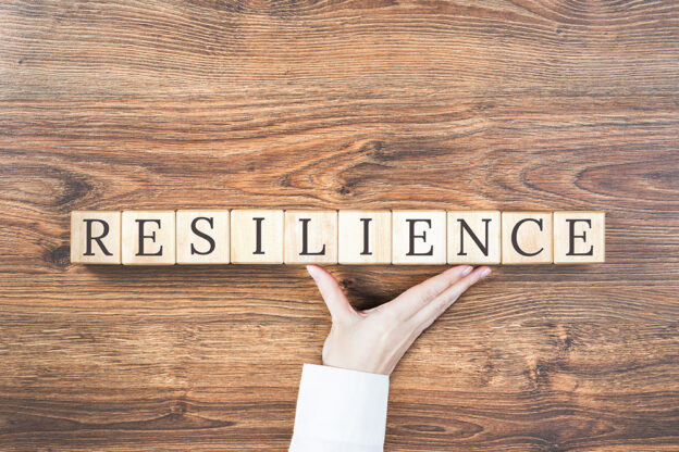 Scrabble tiles on a wooden table spelling out the word "Resilience".