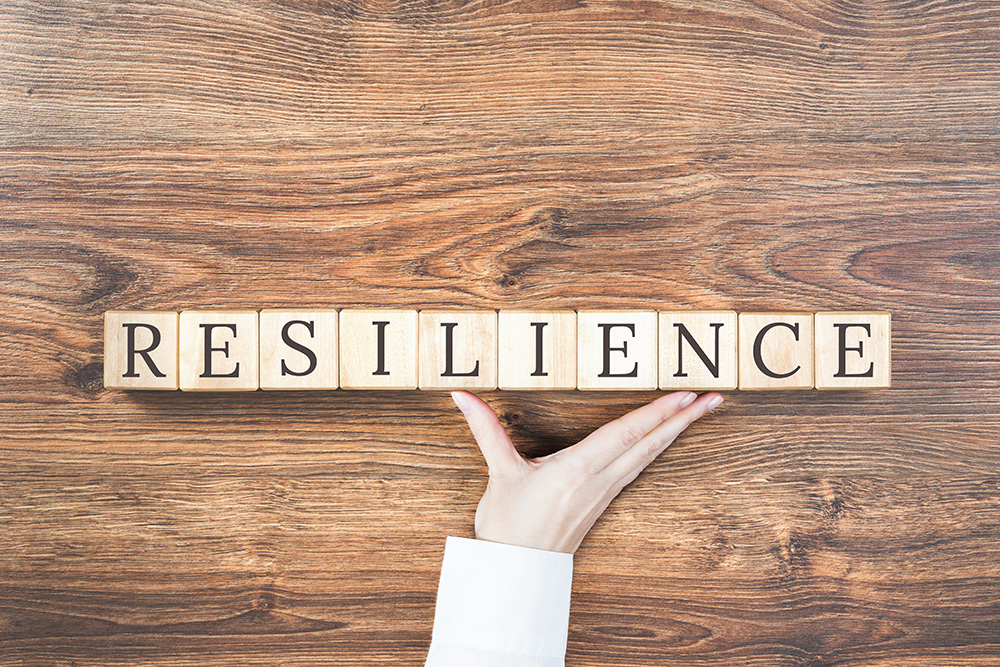 Scrabble tiles on a wooden table spelling out the word "Resilience".