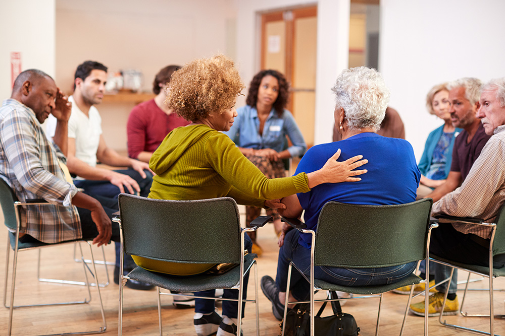 A diverse group of individuals engaged in a self-help therapy session at an Irish community center.